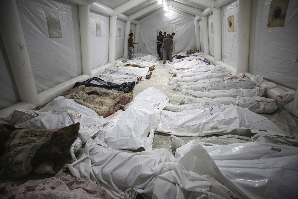 Corpos de palestinos mortos em explosão no hospital Ahli Arab são reunidos em uma tenda no hospital Al Shifa, na Cidade de Gaza — Foto: Abed Khaled/AP