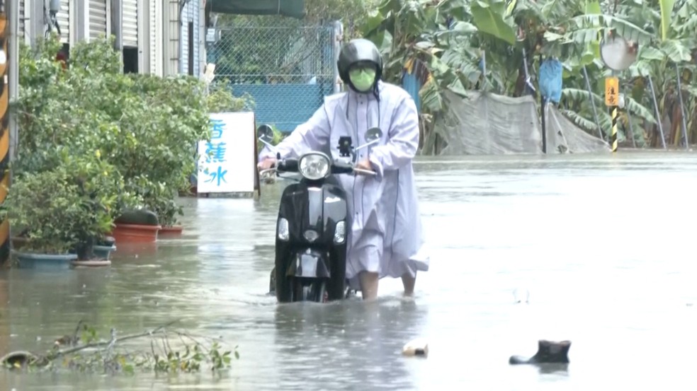 Um homem com uma scooter atravessa a água da enchente durante as fortes chuvas causadas pela passagem do tufão Mekkhala em Taiwan. — Foto: CTS via REUTERS TV