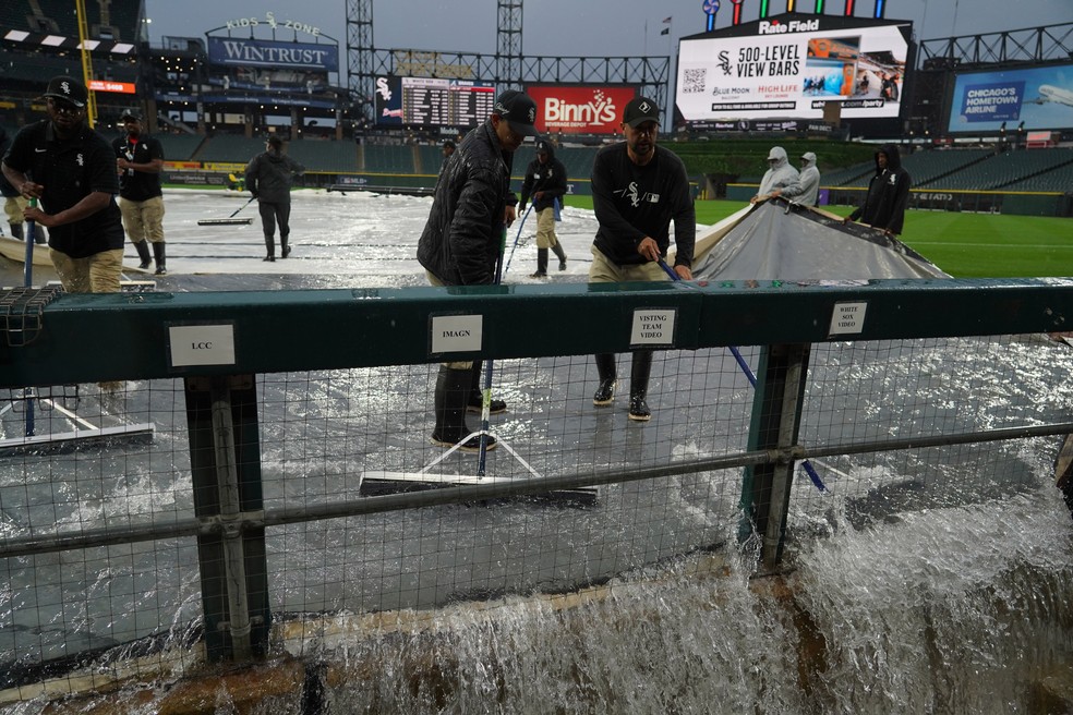 Equipe de manutenção remove água do campo após fortes tempestades passarem pela área de Chicago antes de uma partida de beisebol. — Foto: David Banks / AP