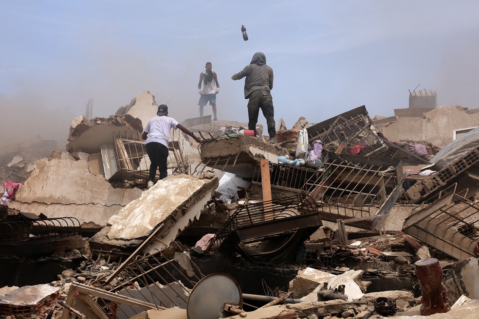 Pessoas procuram por vítimas em meio aos escombros de prédios desabados após os terremotos em La Guaira, Venezuela, em 25 de junho de 2026 — Foto: REUTERS/Gaby Oraa