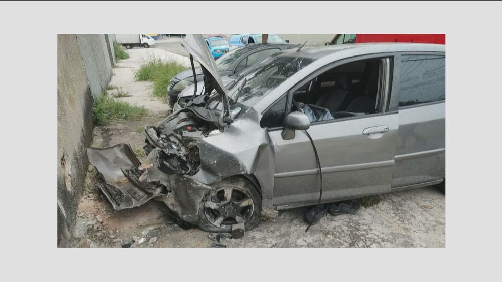Carro jogado de ladeira com corpo de PM dentro ficou completamente destruído após choque com muro — Foto: Reprodução/ GloboNews