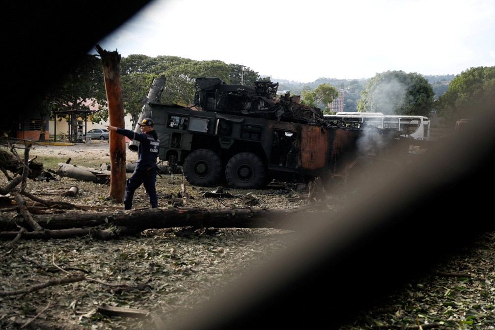 Um bombeiro gesticula ao lado de uma unidade antiaérea destruída na base aérea militar de La Carlota. — Foto: REUTERS/Leonardo Fernandez Viloria