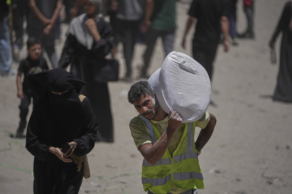 Palestinos carregam sacos de farinha distribuídos pelo Programa Mundial de Alimentos (PMA) na Cidade de Gaza, norte da Faixa de Gaza. — Foto: Foto AP/Jehad Alshrafi