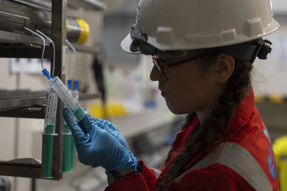 A pesquisadora Alizé Longeau, da Expedição 501, coleta amostras de água de núcleos de perfuração a bordo da plataforma Liftboat Robert, no Atlântico Norte, na madrugada de 20 de julho de 2025. — Foto: Carolyn Kaster/AP