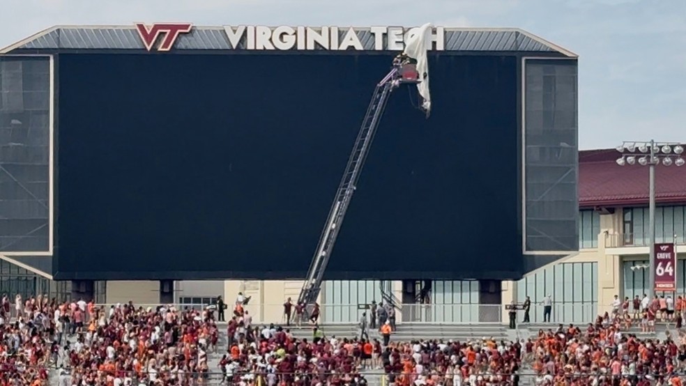 Funcionários em um elevador trabalham para resgatar um paraquedista que caiu no placar do Lane Stadium antes do jogo de futebol americano universitário da Virginia Tech — Foto: Ben Walls/WRIC8 via AP