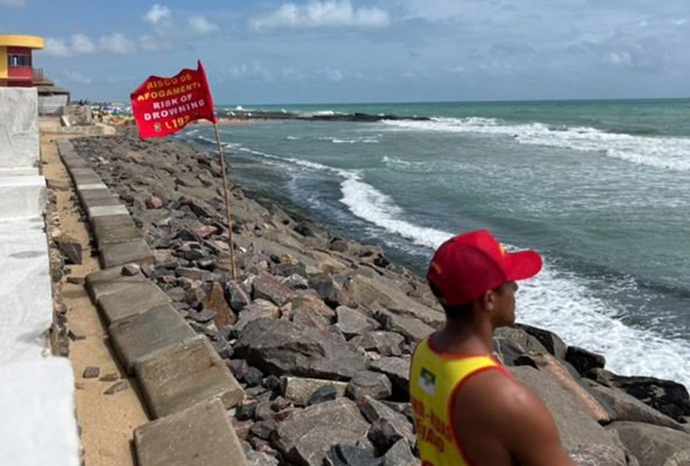Bombeiro perto de bandeira que indica risco de afogamento em praia do RN — Foto: Rianny Lima/CBMRN