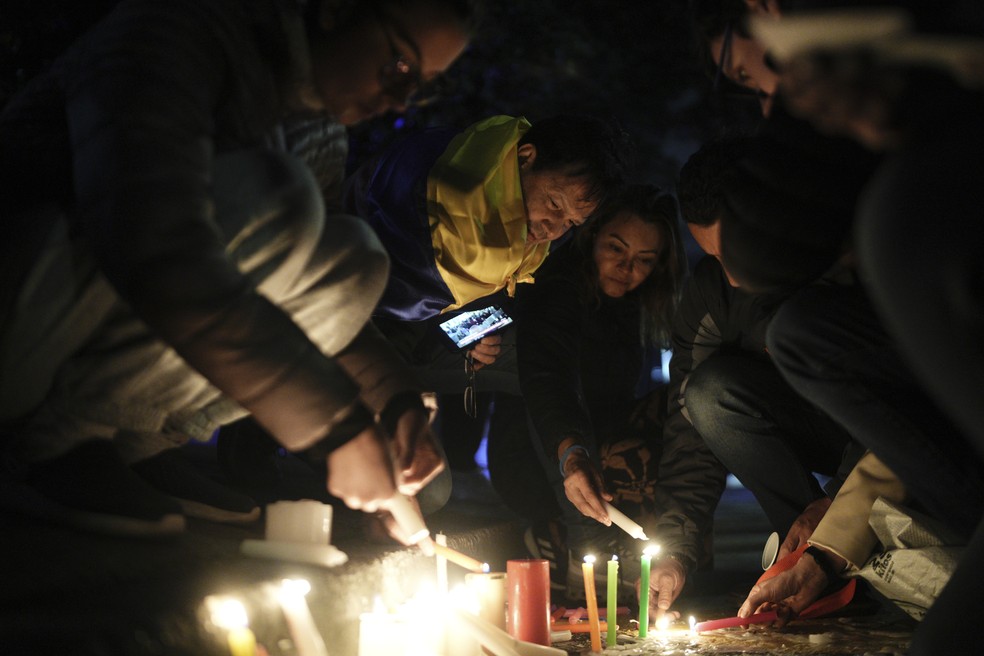 Apoiadores de Uribe acendem velas em homenagem ao político em frente ao hospital Santa Fé em Bogotá — Foto: Ivan Valencia/AP