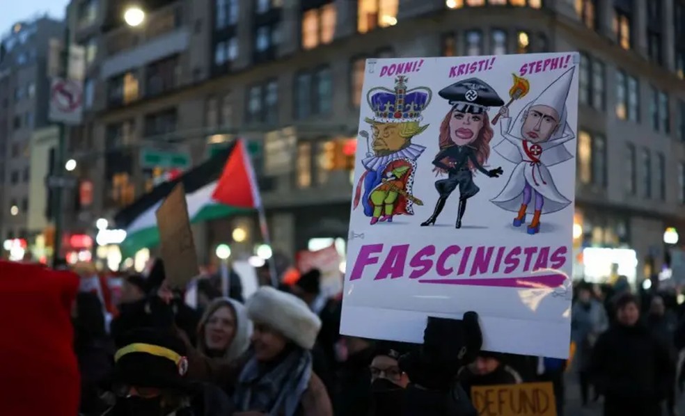 Manifestantes em Nova York retratam Stephen Miller ao lado de Kristi Noem e Donald Trump — Foto: Getty Images