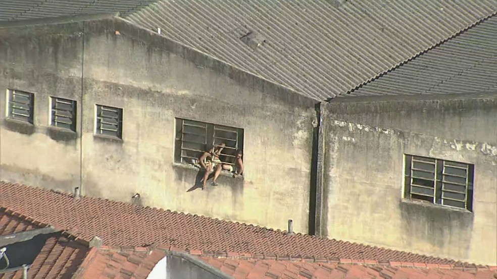 Pessoas penduradas na janela de prédio em chamas em Ramos, na Zona Norte do Rio — Foto: Reprodução/ TV Globo