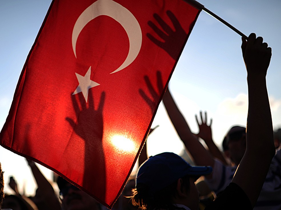 Manifestantes levantam bandeira da Turquia em protesto na praça Taksim, em Istambul. — Foto: Bulent Kilic/AFP