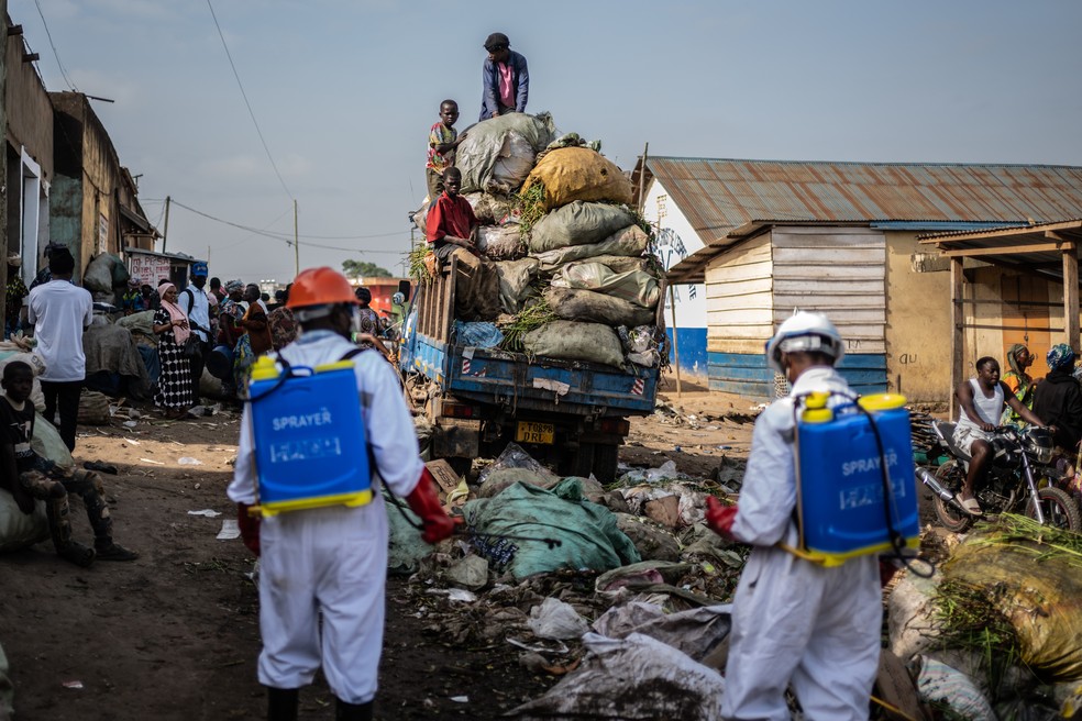 Trabalhadores de saneamento do governo da cidade de Bunia pulverizam desinfetante na área do mercado central, perto de um caminhão de lixo, na província de Ituri, enquanto continuam os esforços para combater o surto de Ebola em Bunia — Foto: AP/Moses Sawasawa
