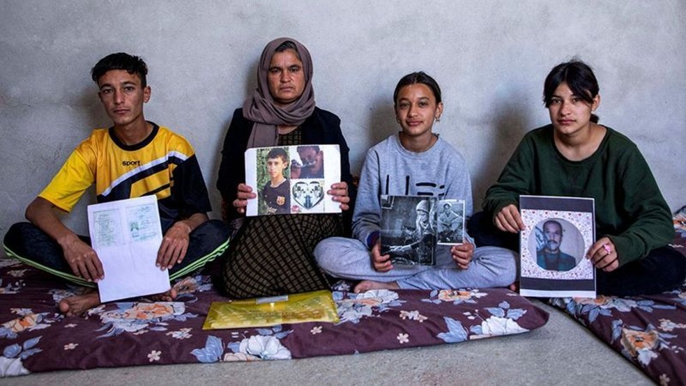 Abril de 2023: Bahar e seus três filhos seguram fotos de seus parentes desaparecidos — Foto: BBC