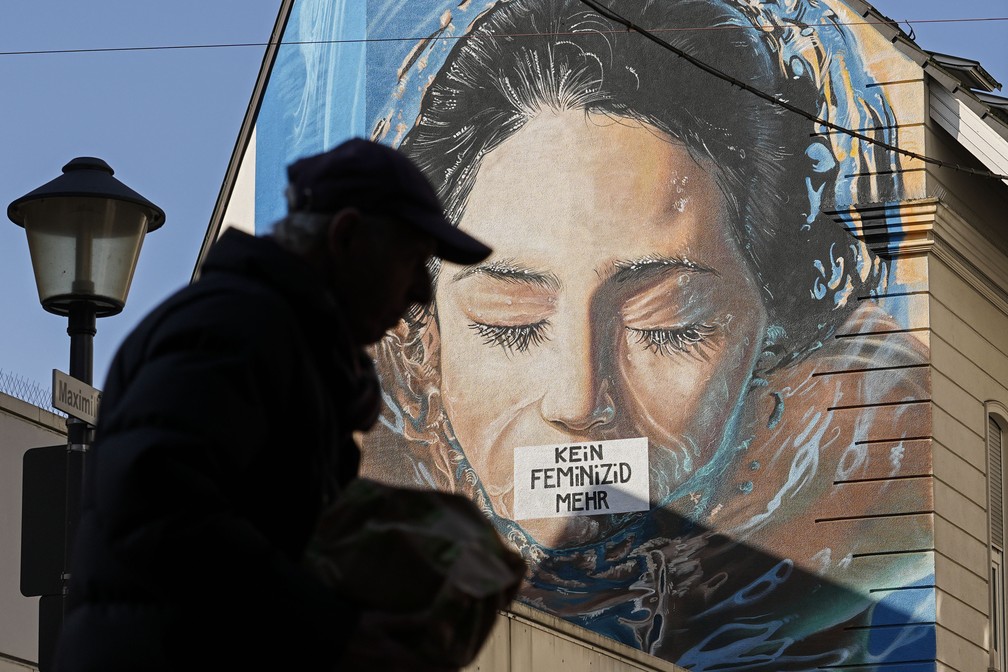 Homem passa por mural onde se lê "não mais feminicídio" em Gelsenkirchen, na Alemanha, no Dia Internacional da Mulher — Foto: Martin Meissner/AP Photo