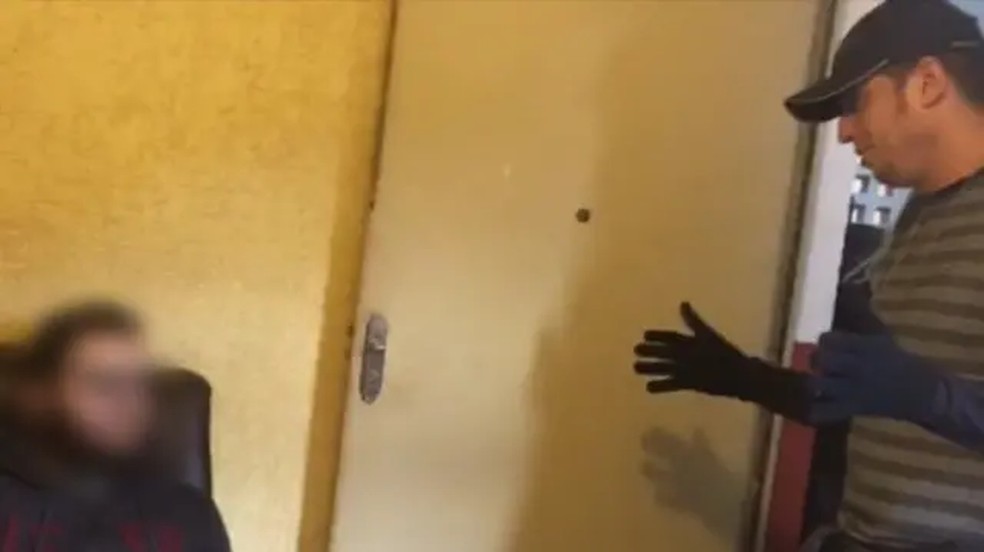 Lubasa (rosto borrado, à esq.) é interrogado por policial no momento de sua prisão. — Foto: Polícia Federal do Brasil/BBC