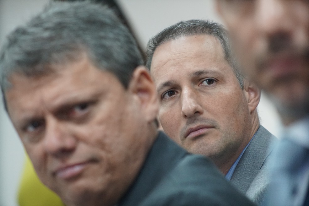 O secretário da Segurança Pública de SP, Guilherme Derrite (PL), atrás do governador Tarcísio de Freitas (Republicanos). — Foto: Rogério Cassimiro/Secom/GESP