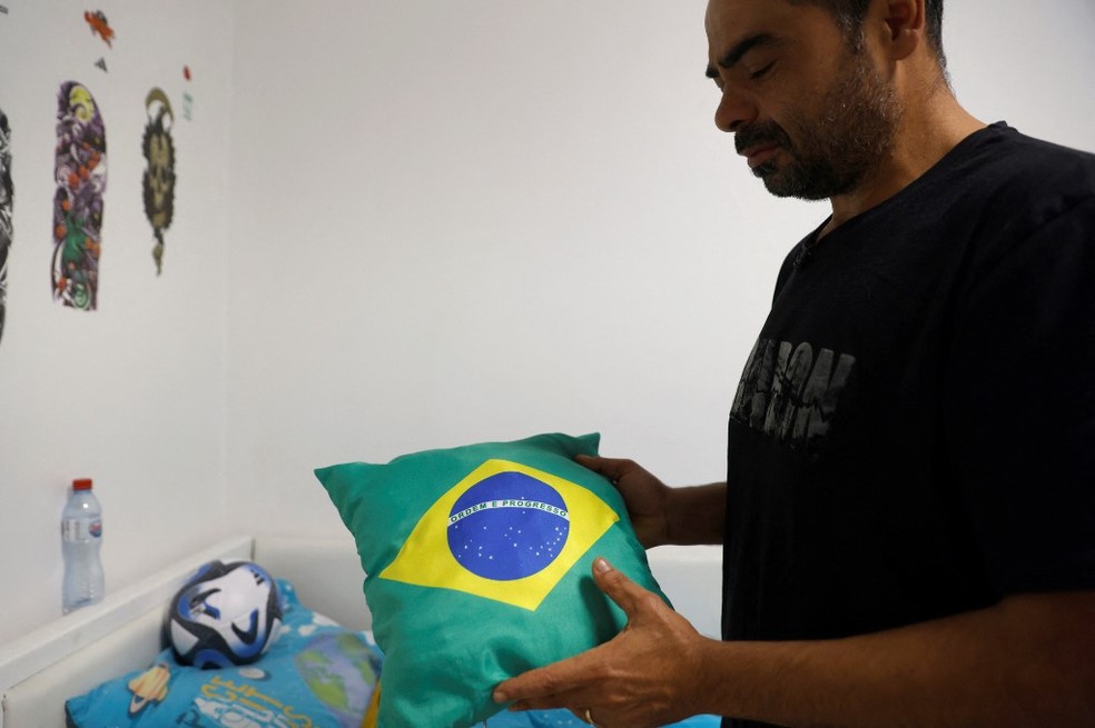 Ibrahim Ibrahim mostra almofada com a bandeira do Brasil que o filho de 11 anos, morto em bombardeio, tinha em sua cama — Foto: Jalaa MAREY / AFP
