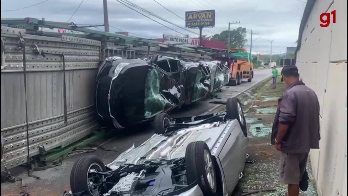 Carro fica destruído após cair de caminhão-cegonha que entalou em