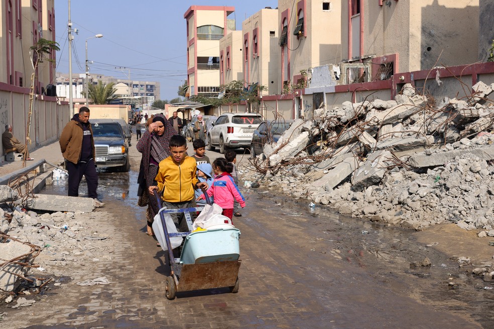 Palestinos passam por escombros em Rafah, no sul da Faixa de Gaza — Foto: Saleh Salem/Reuters