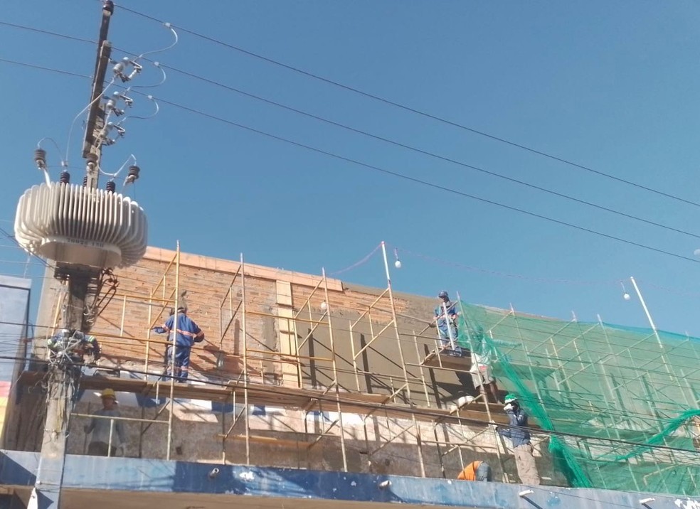 Operários trabalhando em obra perto da rede elétrica