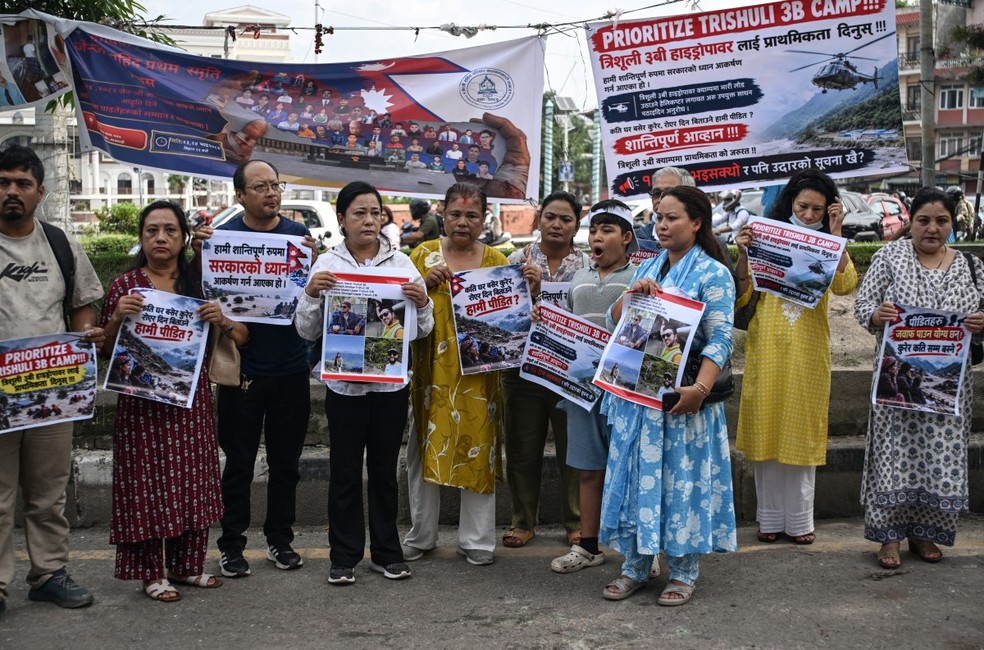 Familiares e parentes das vítimas desaparecidas das enchentes repentinas de 26 de agosto seguram cartazes em protesto para pressionar o governo a intensificar as buscas, em Katmandu, em 7 de setembro de 2026. — Foto: PRAKASH MATHEMA / AFP