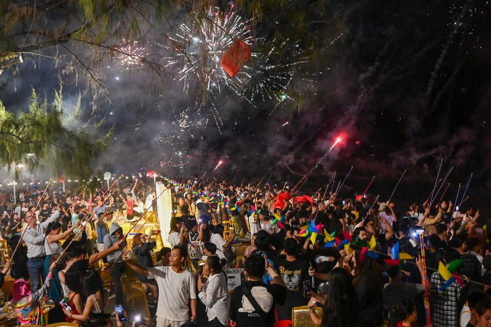 Pessoas se reúnem para assistir os fogos de artifício em celebração ao novo em uma praia em Sihanoukville, no Cambodja. — Foto: Tang Chhin Sothy/ AFP
