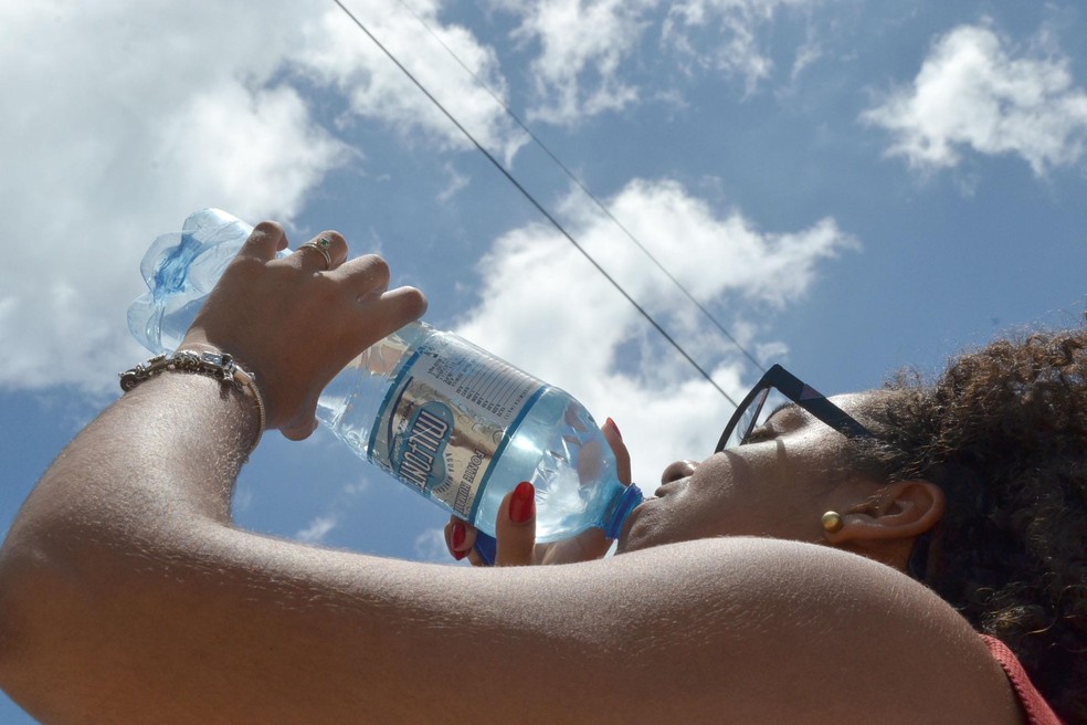 Mulher bebe água na praia do Farol da Barra, em Salvador, em 13 de novembro — Foto: Romildo de Jesus/Futura Press/Estadão Conteúdo