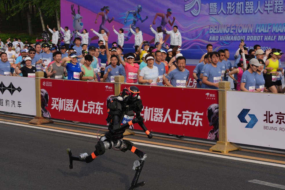Robô humanoide corre ao lado de humanos em competição na China neste domingo (19) — Foto: Ng Han Guan/AP