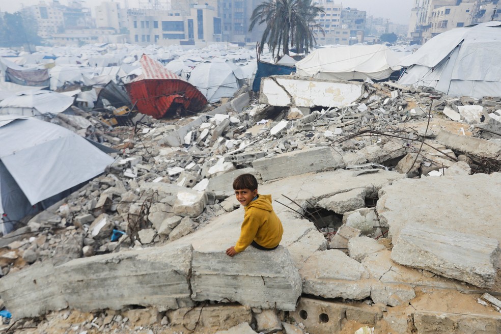 Menino senta em escombro perto de acampamento para refugiados na Cidade de Gaza, em 16 de janeiro de 2025. . — Foto: Mahmoud Issa/Reuters