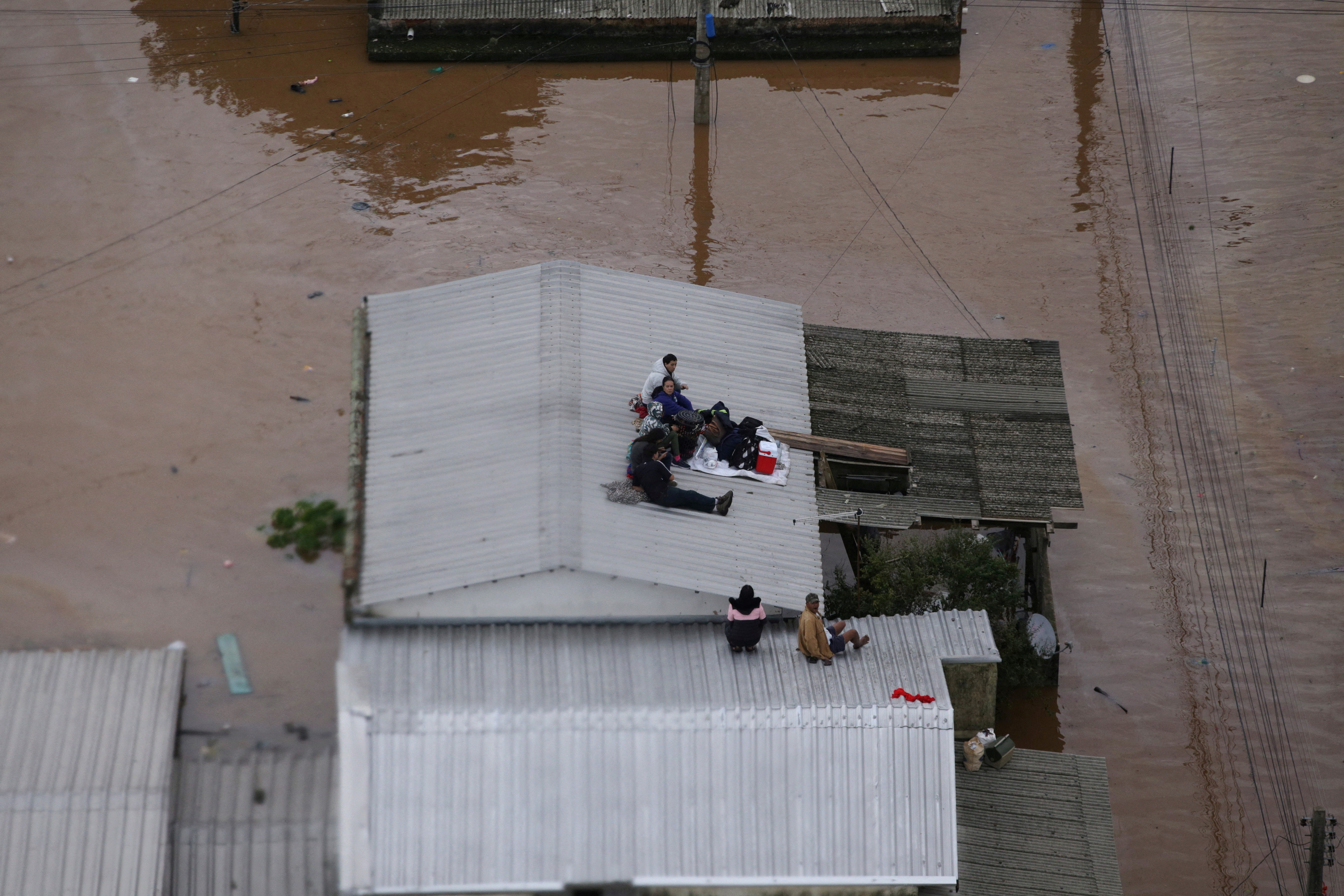 Moradores aguardam resgate no telhado de casa em Canos, no Rio Grande do Sul, no dia 4 de maio de 2024 — Foto: REUTERS/Renan Mattos
