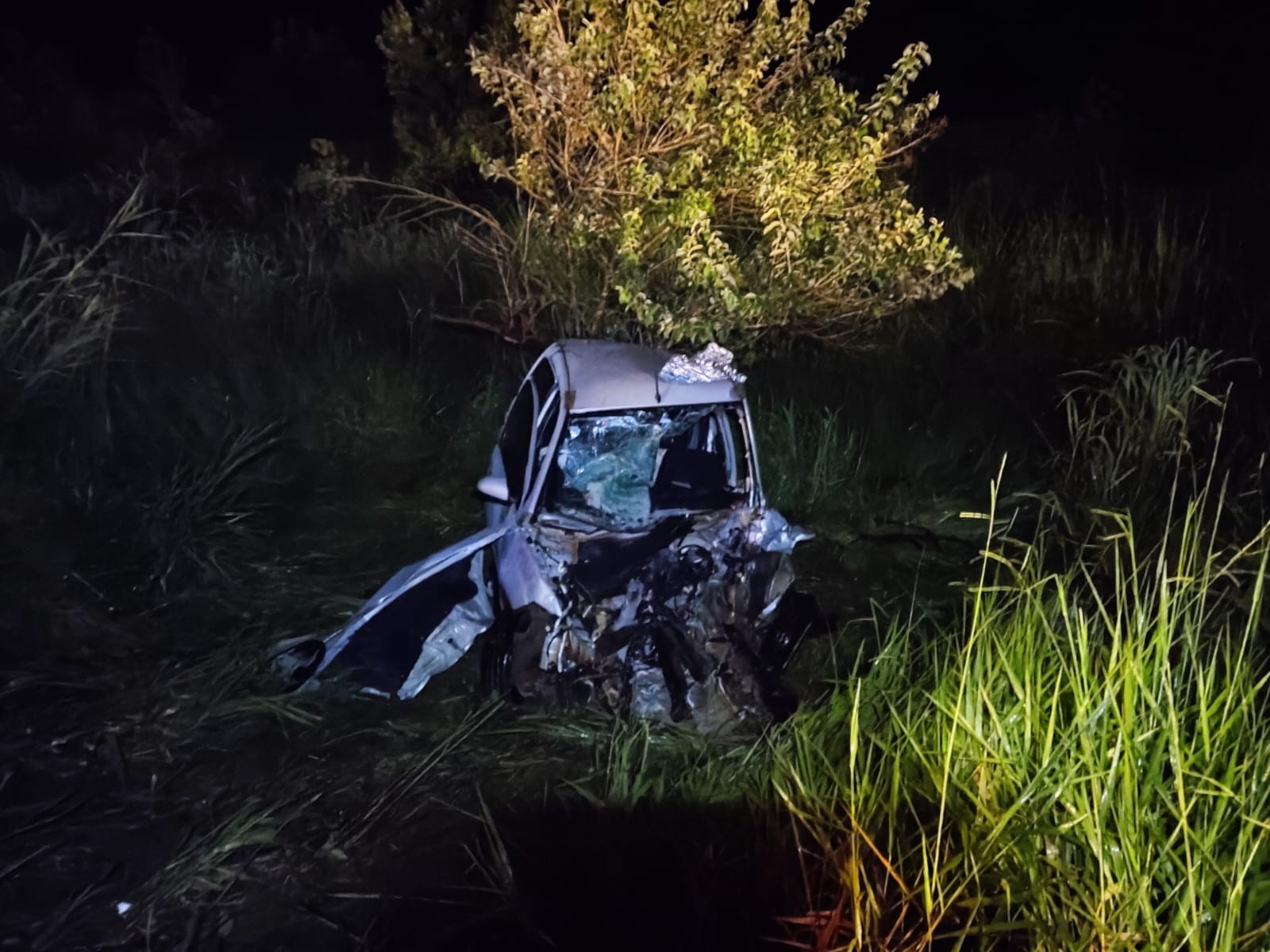 Passageira morre e motorista fica ferido após carro bater em ônibus e caminhão e ficar destruído em MG