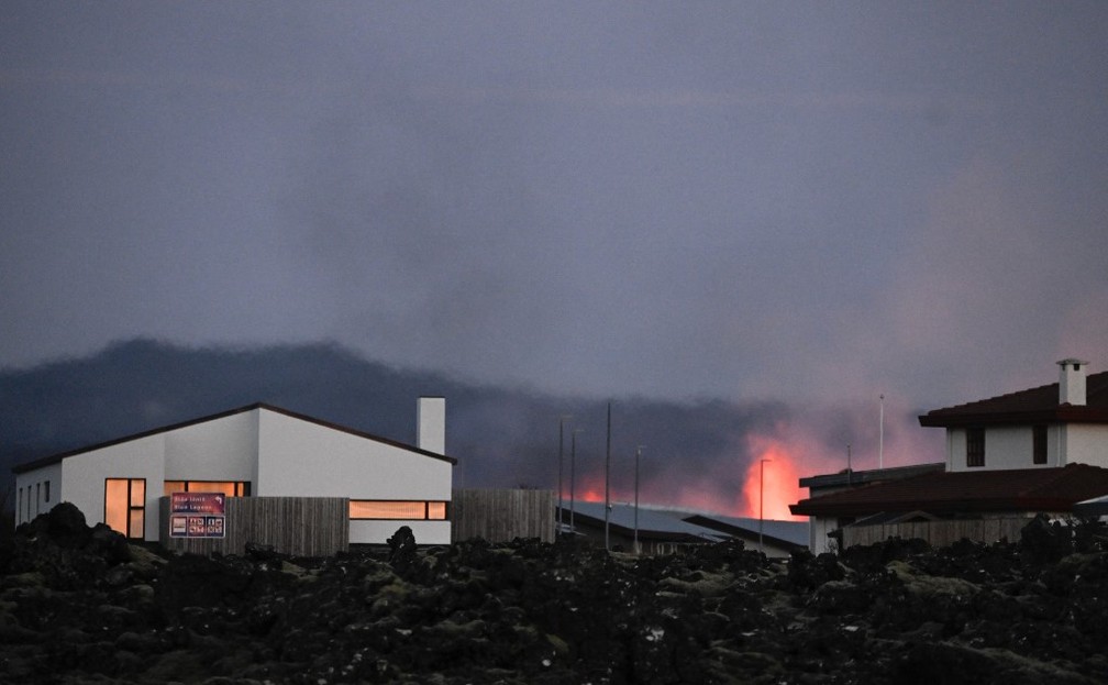 Explosões de lava são vistas perto de casas na cidade de Grindavik, no sudoeste da Islândia, após a erupção vulcânica deste 14 de janeiro. — Foto: Halldor KOLBEINS/AFP
