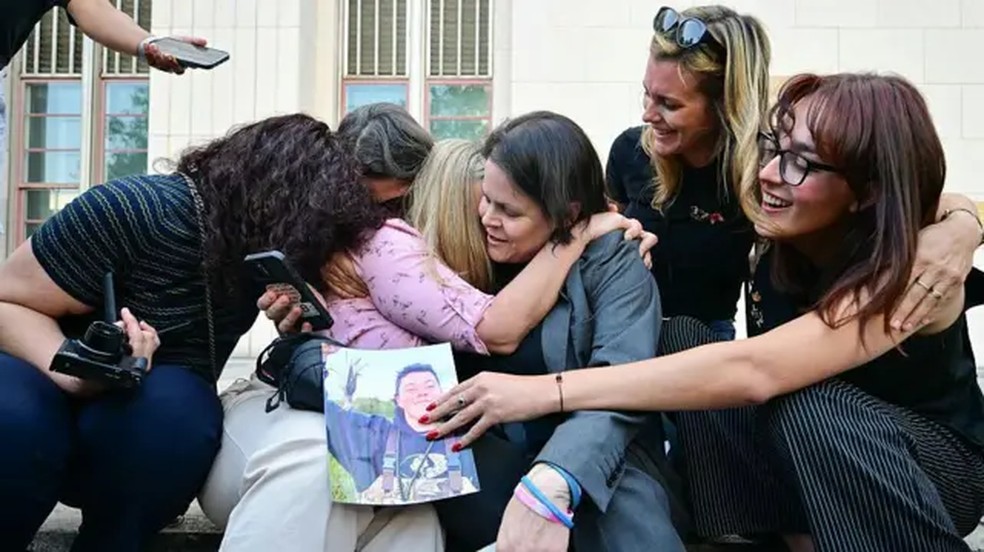 Grupo de mulheres segura imagem de rapaz — Foto: AFP via Getty Images via BBC
