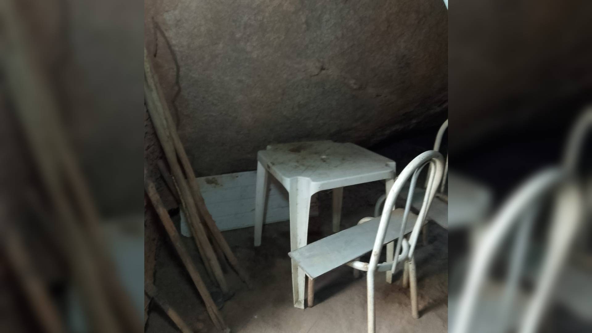 Interior da 'casinha' construída entre duas rochas no CE: à esquerda, ferramentas de trabalho encostadas na parede; mesa também é usada para pôr ferramentas — Foto: Reprodução