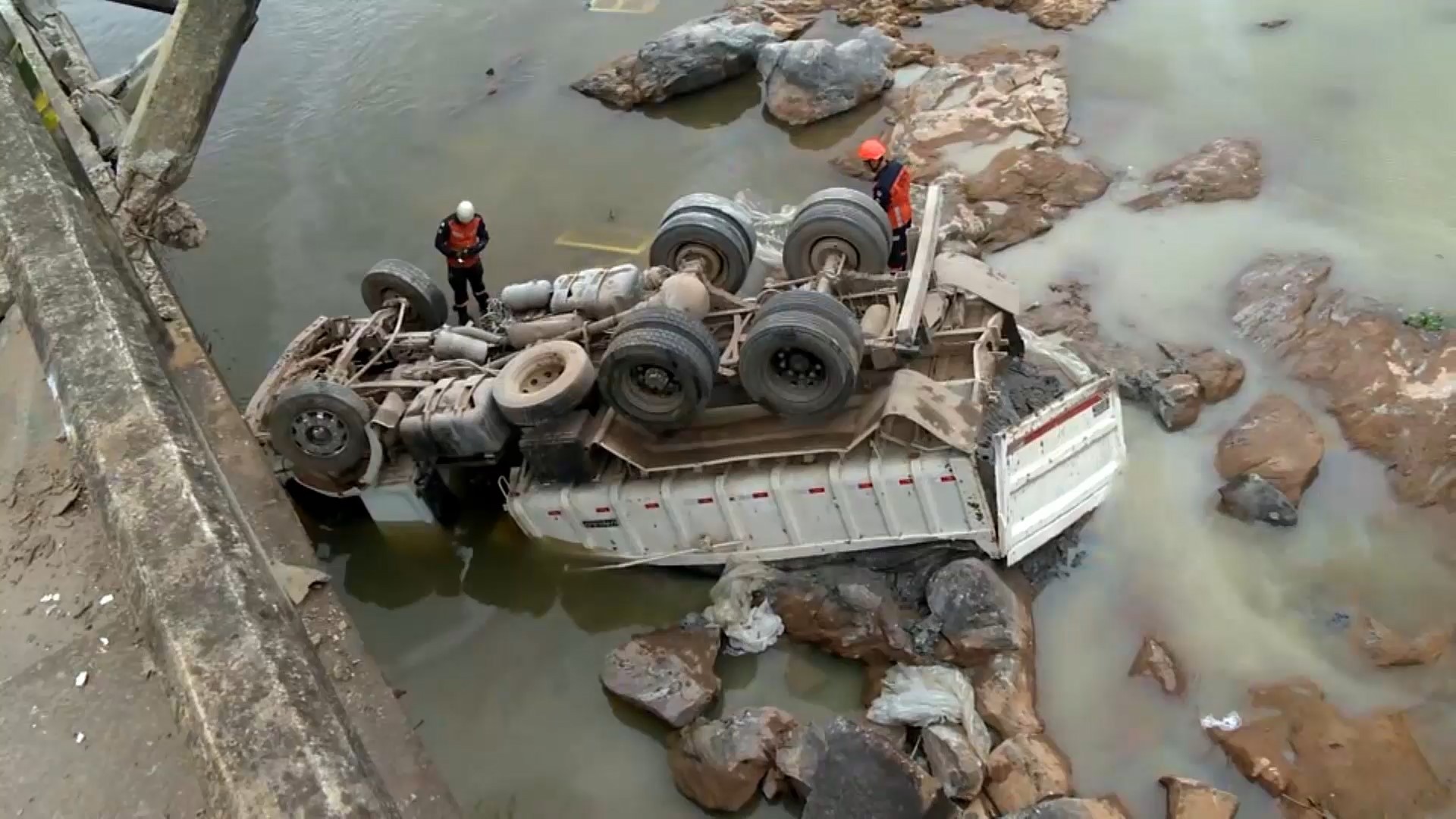 Caminhão carregado com areia tomba, cai de ponte em rio e deixa um morto e um ferido no ES