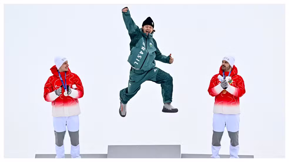 O esquiador brasileiro Lucas Pinheiro pula no ponto mais alto do pódio após ser campeão do slalom gigante nos Jogos Olímpicos de Inverno — Foto: Fabrice Coffrini/AFP