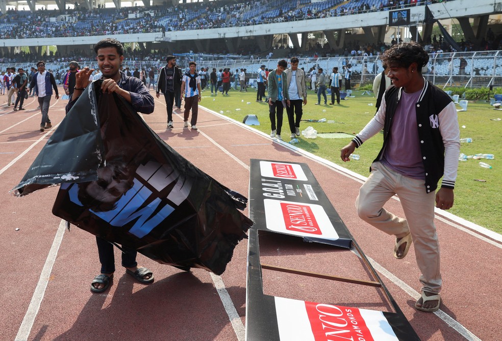 Fã arranca um cartaz publicitário após o astro do futebol argentino Lionel Messi deixar o estádio Vivekananda Yuva Bharati Krirangan durante sua turnê pela Índia — Foto: REUTERS/Sahiba Chawdhary