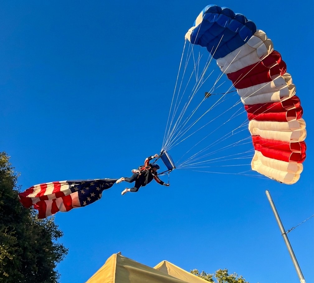 VÍDEO: Paraquedista amarrado à bandeira gigante dos EUA se enrosca em árvore e cai sobre tenda