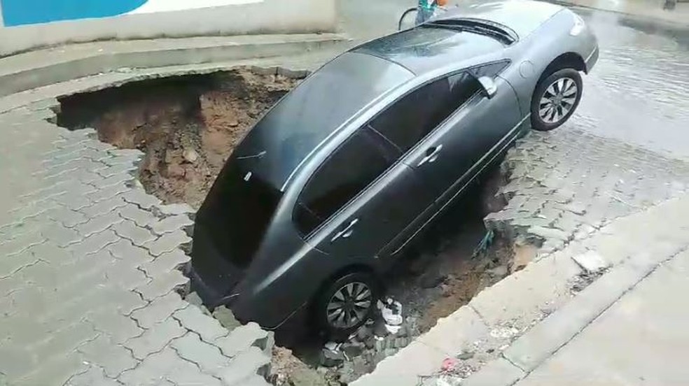 Cratera engole carro na Rua Araçatuba, no Bairro Curió, em Fortaleza, durante a chuva da manhã desta sexta-feira (14). — Foto: Reprodução