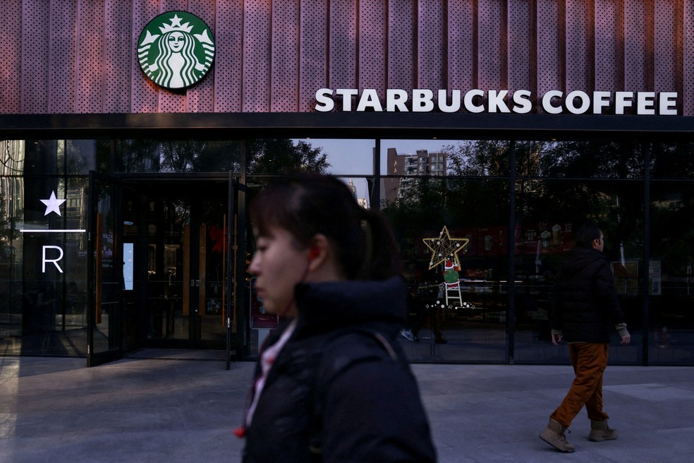 Pessoas passam em frente a uma cafeteria da Starbucks em Pequim, na China. — Foto: REUTERS/Tingshu Wang