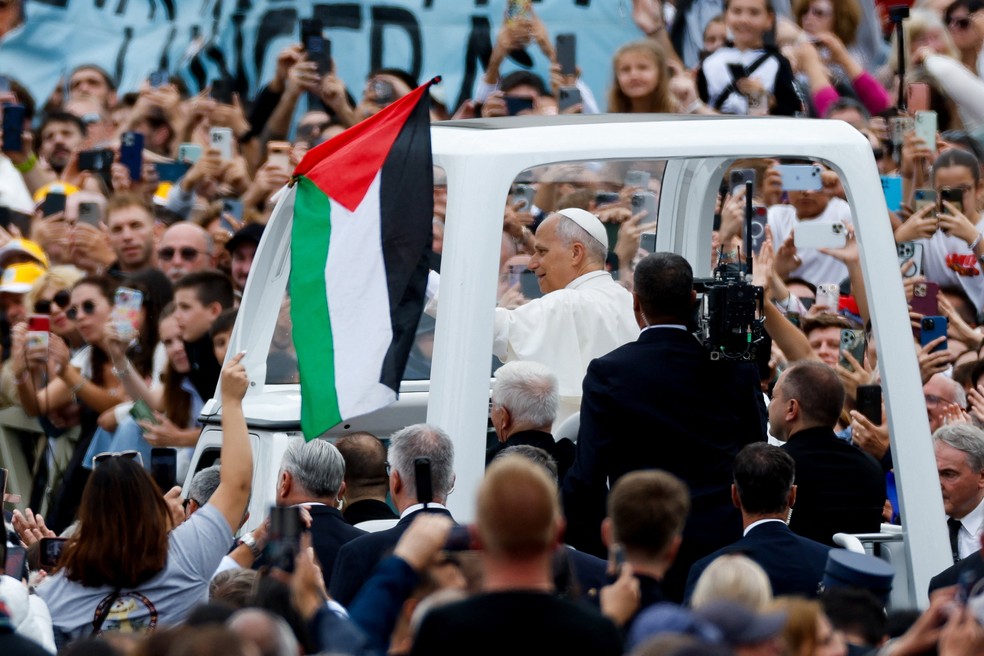 Fiel ergue bandeira da Palestina perto do papa Leão XIV durante passeio de papamóvel após missa na Praça de São Pedro, no Vaticano, em 5 de outubro de 2025. — Foto: REUTERS/Remo Casilli