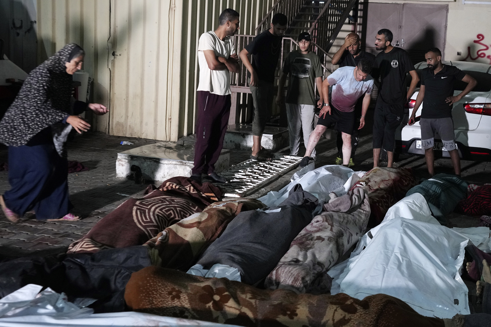 Palestinos ao lado de familiares mortos em bombardeio israelense em Nusseirat, em 6 de junho de 2024 — Foto: Abdel Kareem Hana/AP