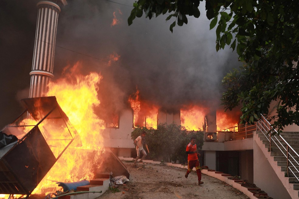 Manifestantes correm em meio a chamas no complexo do Parlamento nepalês durante um protesto em Catmandu, no Nepal, em 9 de setembro de 2025. — Foto: Prabin Ranabhat/AFP