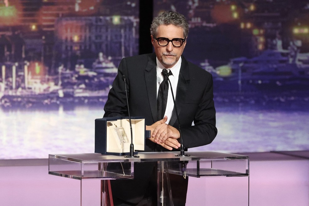 O diretor brasileiro Kleber Mendonça Filho recebe o prêmio de Melhor Ator em nome do ator brasileiro Wagner Moura pelo filme "O Agente Secreto" durante a Cerimônia de Encerramento da 78ª edição do Festival de Cinema de Cannes, em Cannes, sul da França, em 24 de maio de 2025. — Foto: Sameer Al-Doumy/AFP