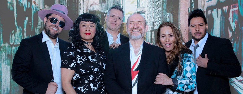 A formação de 2024 do Men at Work, com Colin Hay e Cecilia Noël (backing vocal e esposa do cantor) segurando o braço dele — Foto: Divulgação/Site da banda