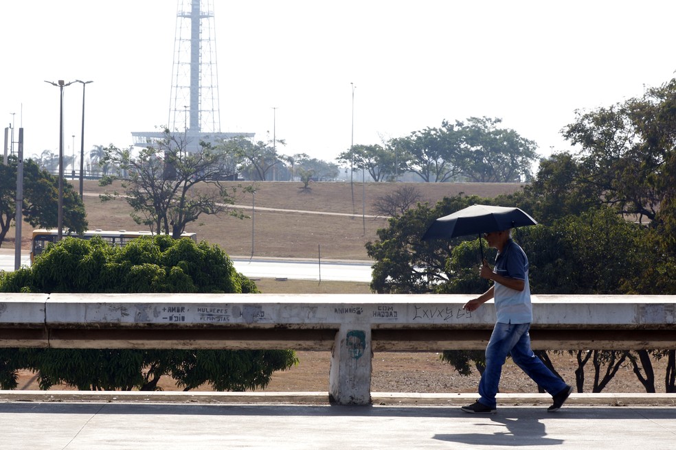 03.09.2024 – Em meio à seca e ao calor intenso, pedestre usa guarda-sol ao atravessar o Setor de Diversões Sul, em Brasília. — Foto: Bruno Peres/Agência Brasil