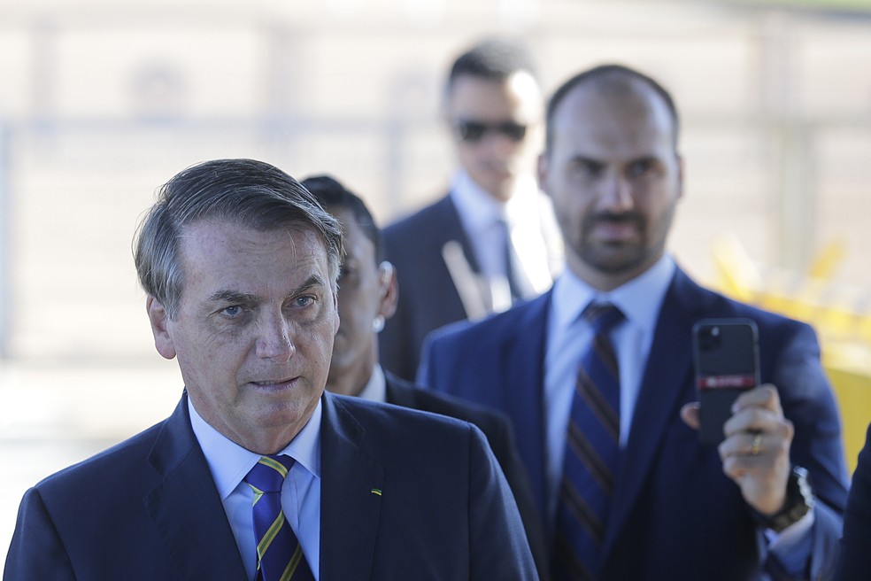 O presidente da República, Jair Bolsonaro, tendo ao fundo seu filho, o deputado federal Eduardo Bolsonaro, ao conversa com a imprensa ao chegar na portaria do Palácio da Alvorada, em Brasília, nesta terça-feira, 13. O presidente levou folhas de sulfite com o discurso do diretor-geral da Organização Mundial de Saúde (OMS), Tedros Ghebreyesus, para consultar durante a conversa com jornalistas e apoiadores. Jornalistas que fazem a cobertura diária do Palácio da Alvorada se retiraram de entrevista concedida pelo presidente após ele estimular apoiadores a hostilizarem os repórteres que estavam no local. — Foto: DIDA SAMPAIO/ESTADÃO CONTEÚDO