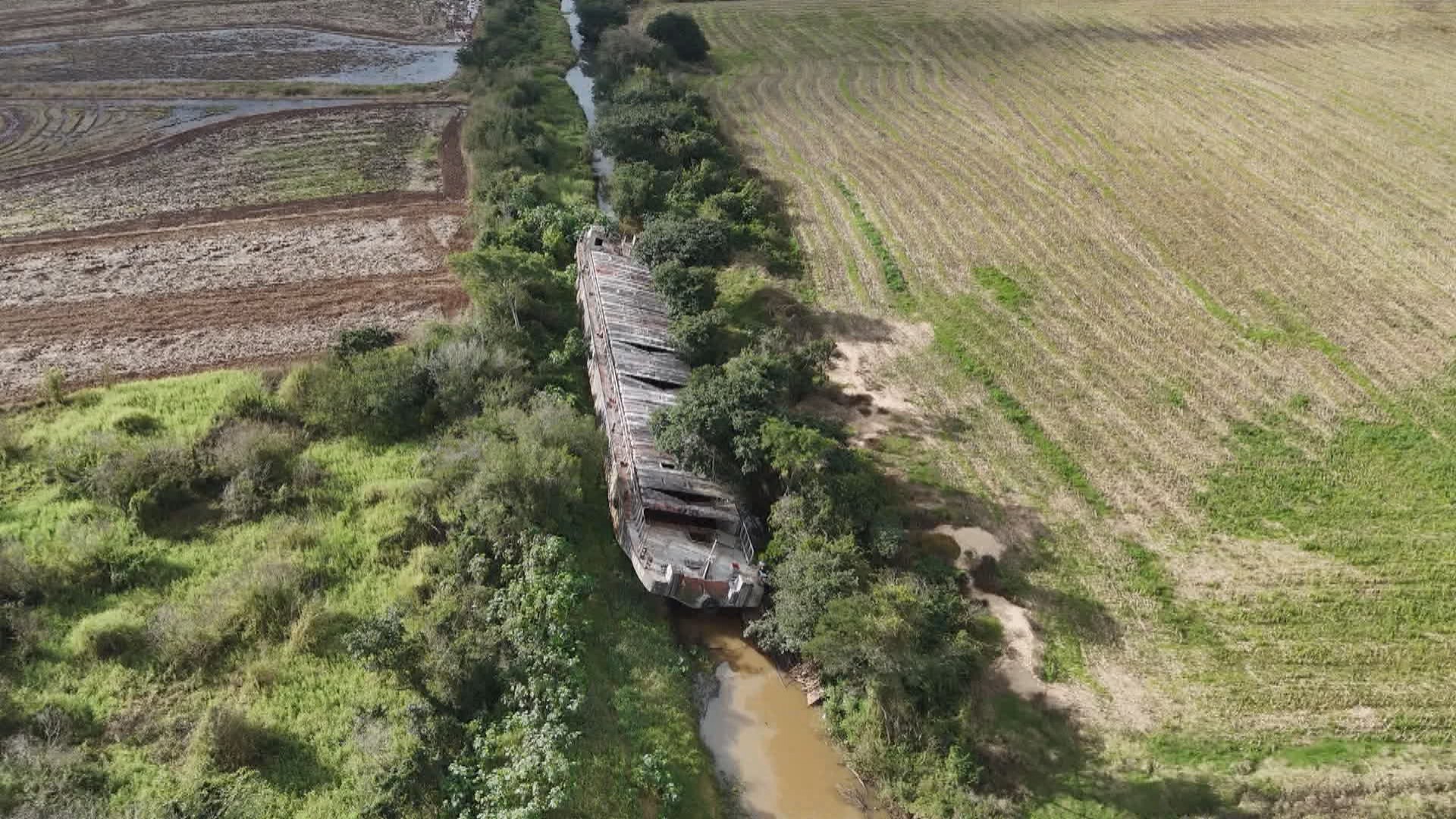 Embarcação encalhada em enchente há mais de um ano ainda bloqueia canal de irrigação no RS; chuvas podem ajudar na remoção