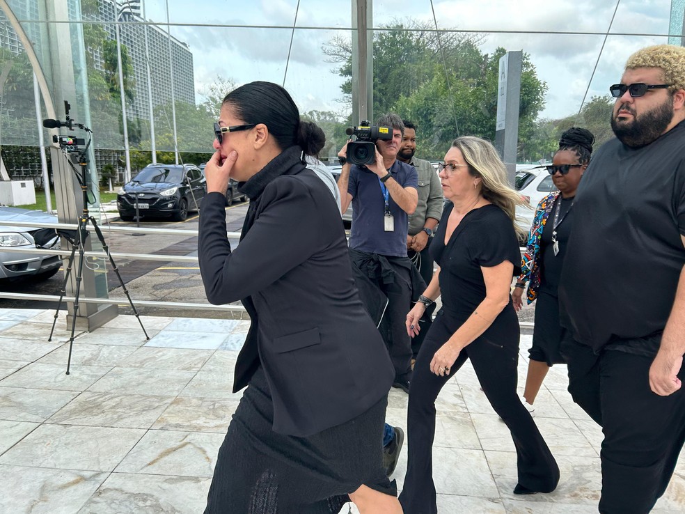 Esposa (com a mão no rosto) e um dos filhos de Maguila, de óculos, chegam para o velório do ex-boxeador na Alesp — Foto: Guilherme Pimentel/TV Globo