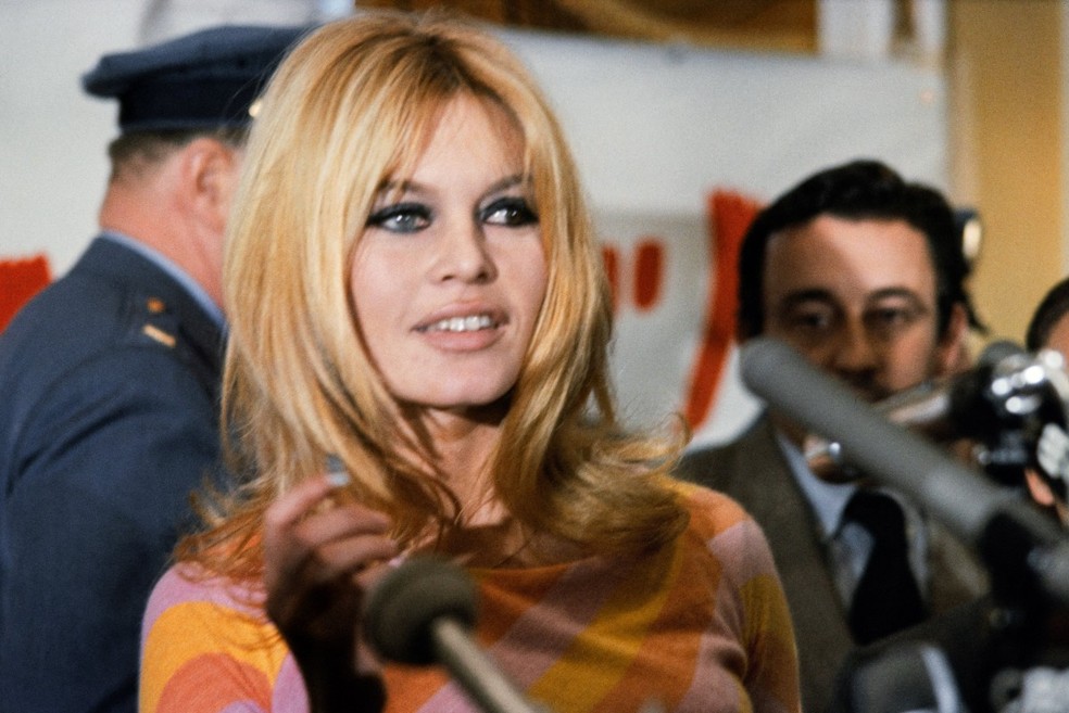 Brigitte Bardot concede uma entrevista coletiva em dezembro de 1965 em Hollywood para o filme "Viva Maria!", dirigido por Louis Malle (ao fundo). — Foto: AFP