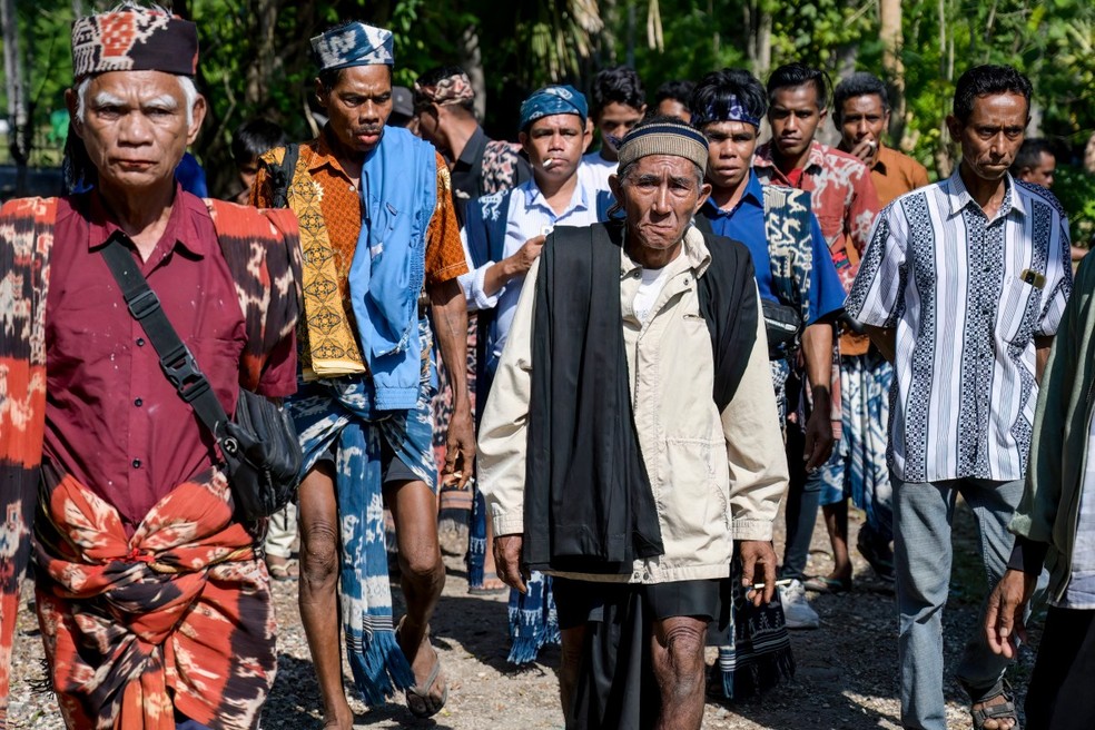 Homens de Sumba, alguns vestindo o tradicional tecido ikat, participando de uma cerimônia fúnebre marapu — Foto: Bay Ismoyo/AFP